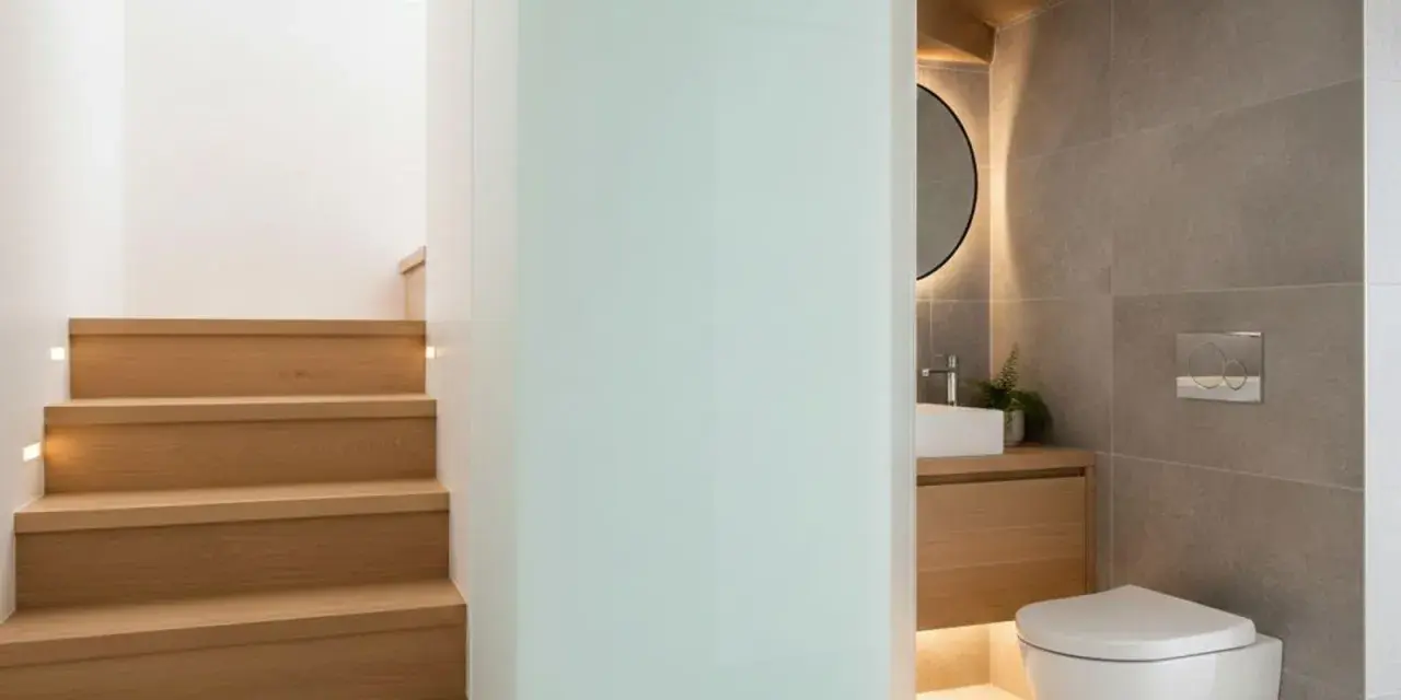 Escaliers en bois menant à un wc sous pente moderne, avec lavabo et miroir rond.