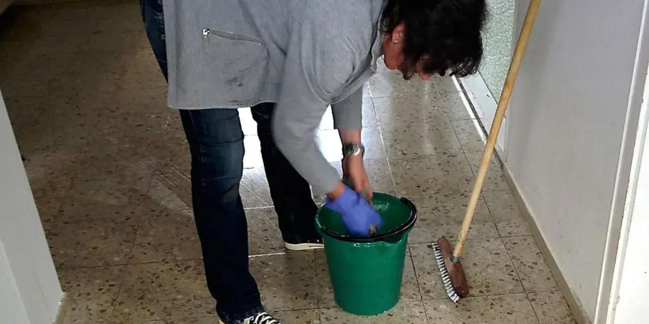 Sprzątaczka w szkole, w niebieskich rękawiczkach, przygotowuje się do pracy. Zastanawiasz się, ile zarabia sprzątaczka w szkole?