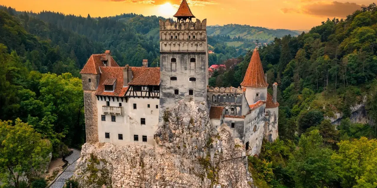 Majestatyczny zamek w Transylwanii, górujący nad lasami o zachodzie słońca.