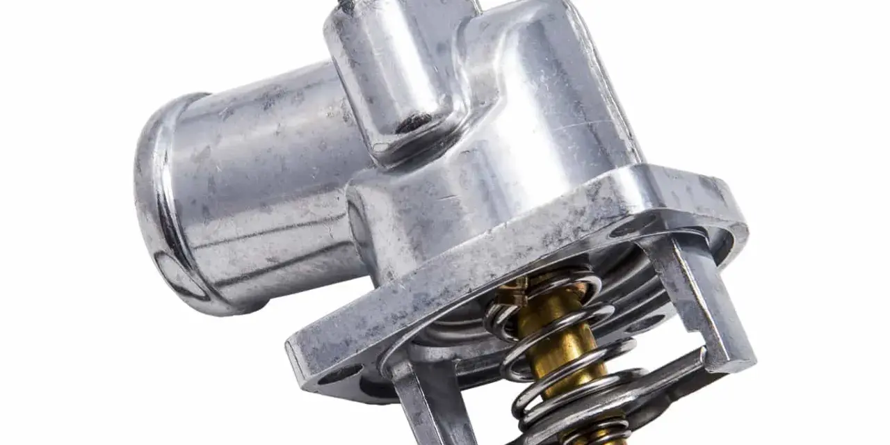 Metalowy termostat w samochodzie z widoczną sprężyną i zaworem. Kluczowy element układu chłodzenia.