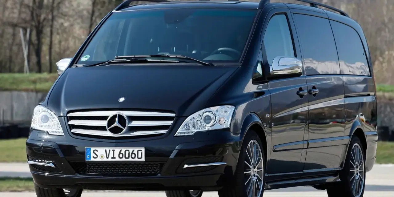 Czarny Mercedes Viano 3.0 V6 z przyciemnianymi szybami i relingami dachowymi, gotowy na podróż.