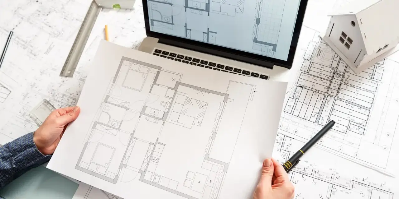 Rysunki techniczne i model domu na biurku. Plan mieszkania od dewelopera w rękach osoby projektującej.