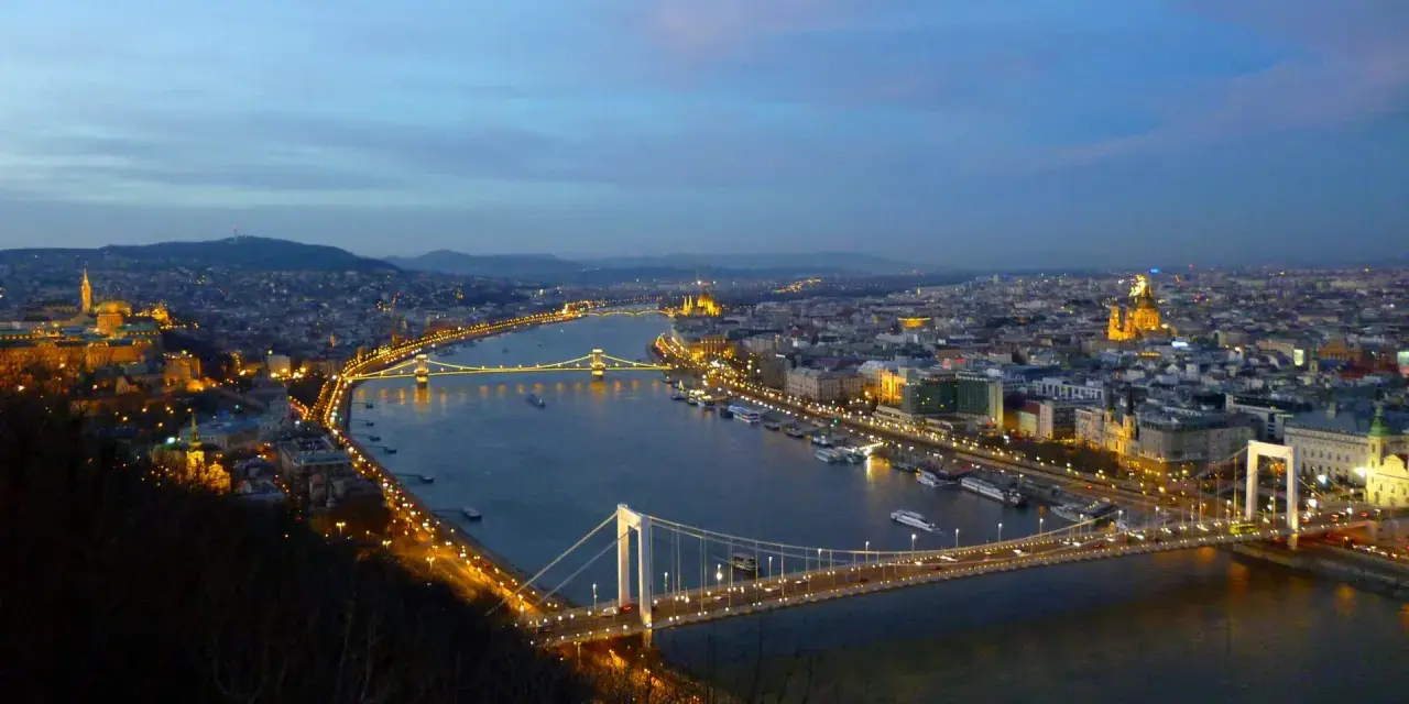 Vista nocturna de Budapest con el río Danubio y sus puentes iluminados, creando un paisaje urbano mágico.