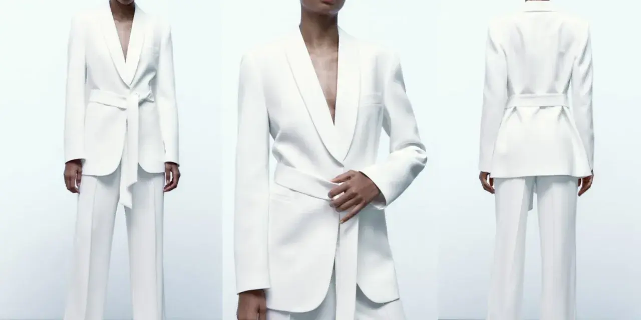Mujer posa con un elegante traje blanco de pantalón y blazer con cinturón. Un look sofisticado para combinar traje blanco mujer.