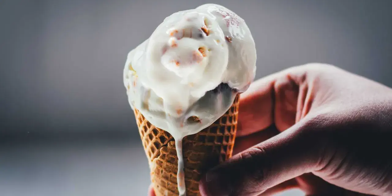 Eine Hand hält ein schmelzendes Rhabarber-Eis in einer Waffel.