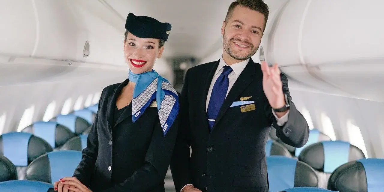 Uśmiechnięta stewardessa i steward w uniformach LOT-u, gotowi do lotu. Marzysz, jak zostać stewardessą? To początek Twojej przygody!