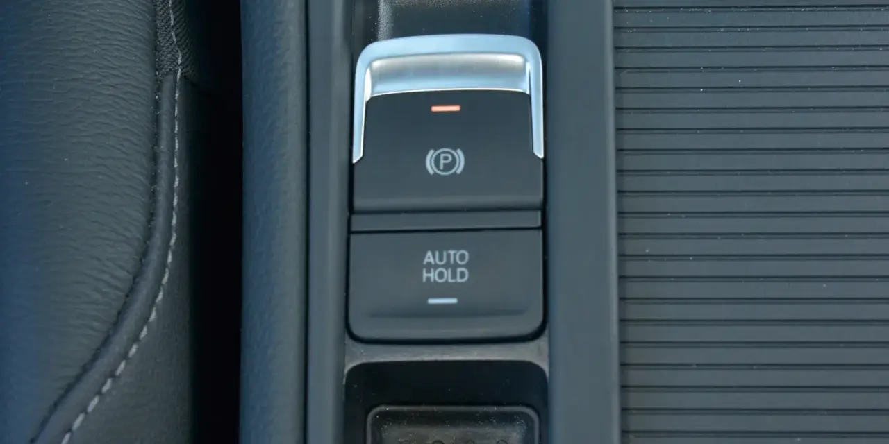 Przycisk AUTO HOLD w samochodzie. To funkcja, która automatycznie utrzymuje pojazd w miejscu po zatrzymaniu.