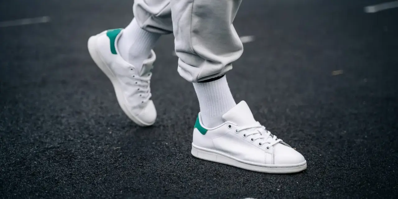 Un paio di sneakers bianche con dettagli verdi, simbolo di stile e comfort. Il loro significato va oltre la moda, rappresentando libertà di movimento.