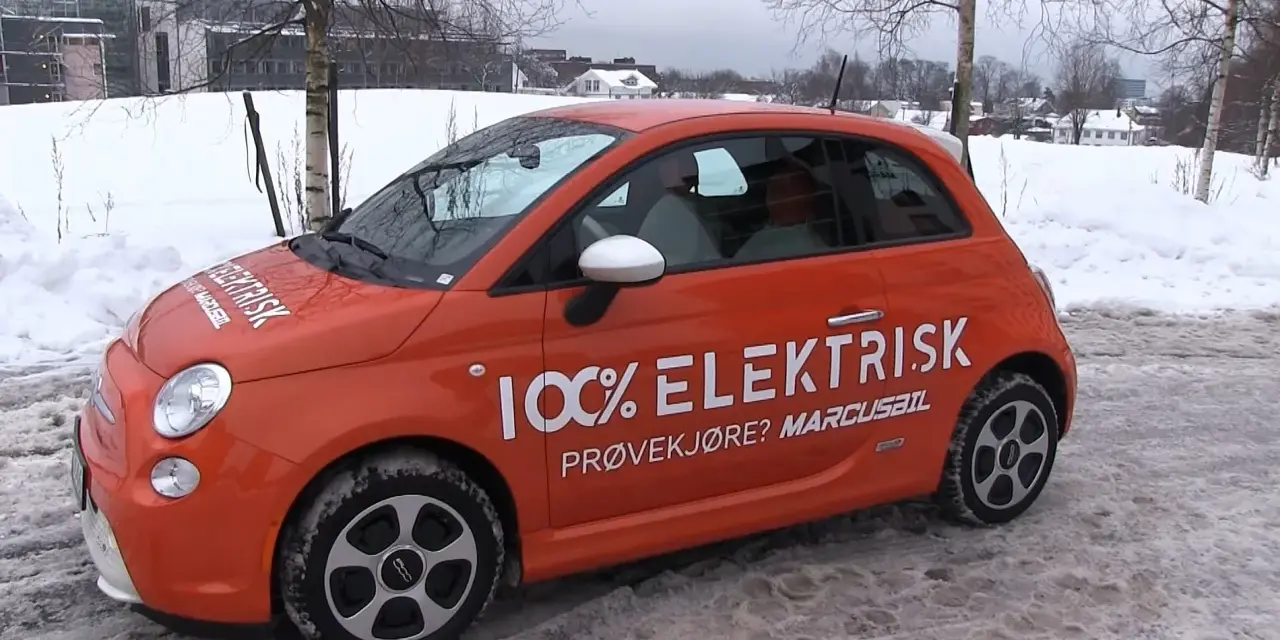 Pomarańczowy Fiat 500e w zimowej scenerii, z napisem "100% ELEKTRISK". Sprawdź zasięg tego elektryka!