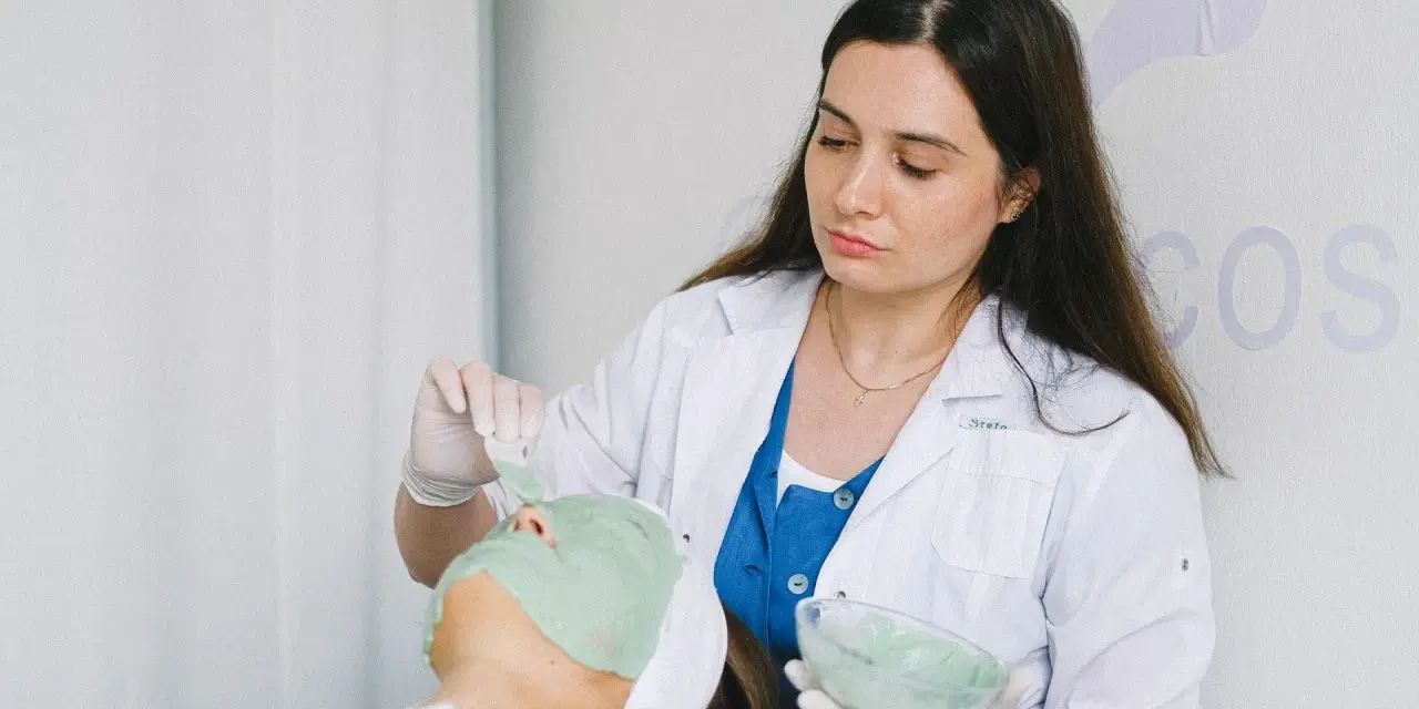 Dermatolog nakłada zieloną maskę na twarz pacjentki.