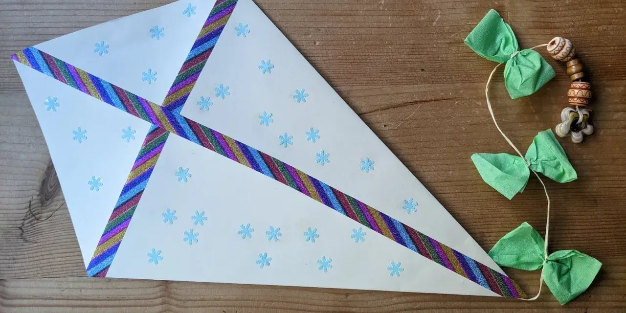 Ein selbstgebastelter Drachen mit Schneeflockenmuster und bunten Bändern. Perfekt für schnelle bastelideen einfach und schnell.