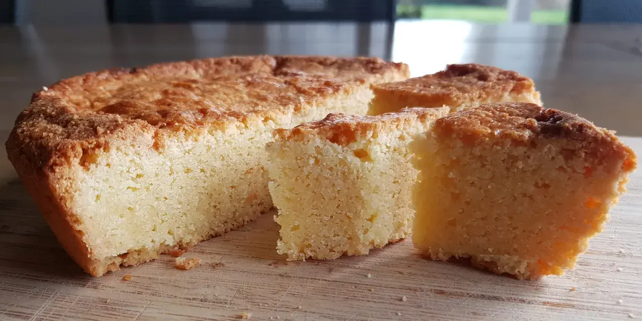 Un delicioso pastel bretón, dorado y esponjoso, cortado en porciones sobre una tabla de madera.
