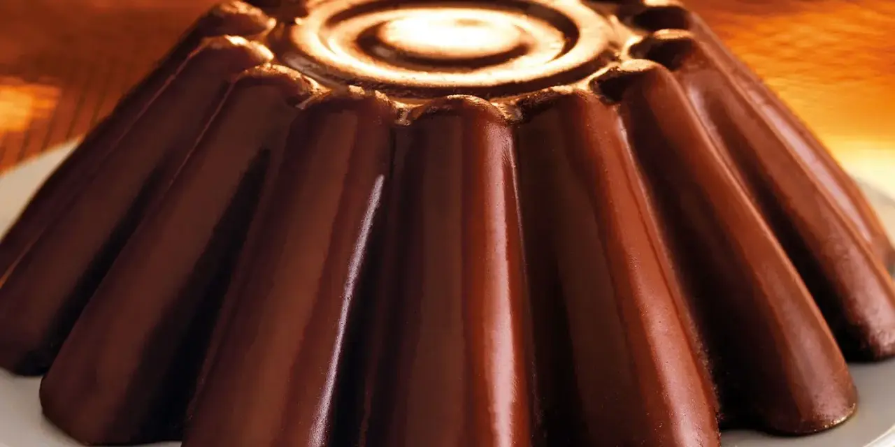 Budino al cioccolato lucido e invitante, con un disegno a spirale al centro e un bordo decorato.