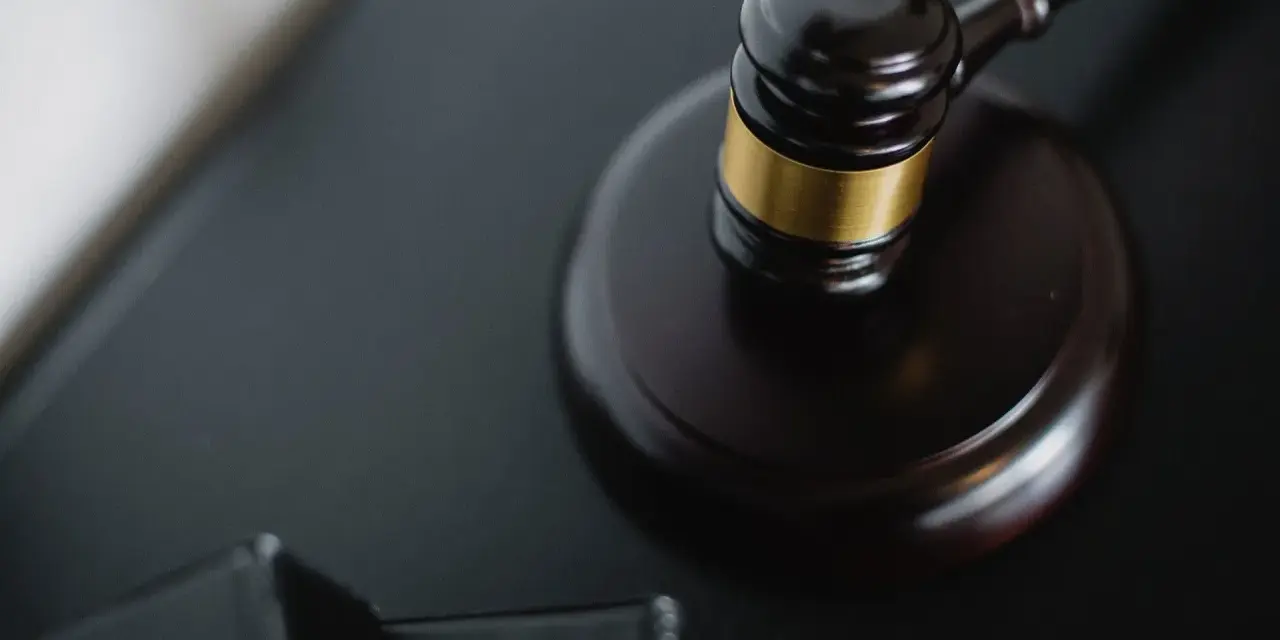 Młotek sędziowski na czarnym tle, symbol sprawiedliwości. Może symbolizować ważną decyzję, jak w przypadku pierwszego świadka koronnego w Polsce.
