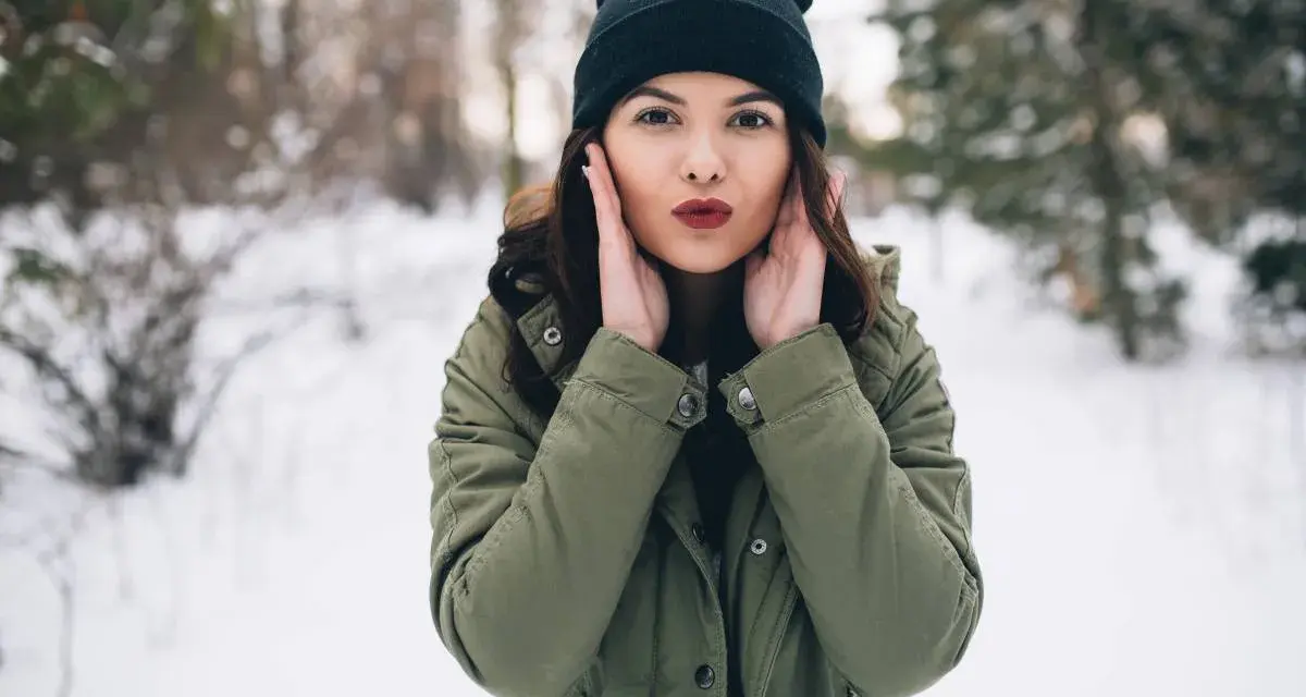 Zastanawiasz się, jaki szalik do zielonej kurtki? Ta dziewczyna w zimowym lesie ma czarną czapkę i zieloną kurtkę.
