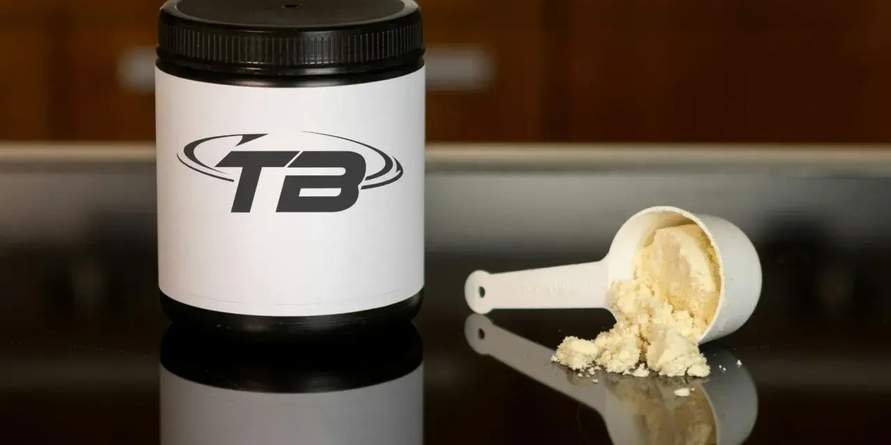 En burk med proteinpulver och en skopa med pulver. Frågan om hur mycket proteinpulver per dag är relevant för att optimera träningen.