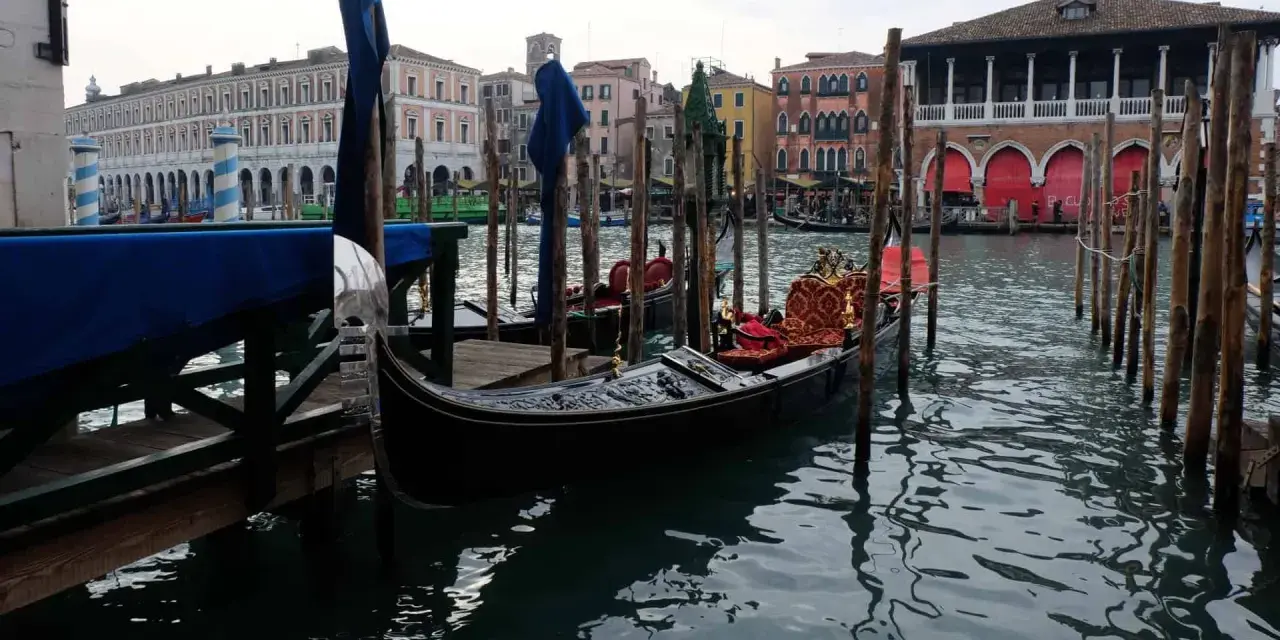 Gondole ormeggiate in un canale veneziano, con palazzi storici sullo sfondo. Immagine che evoca il fascino di quando è stata costruita Venezia.