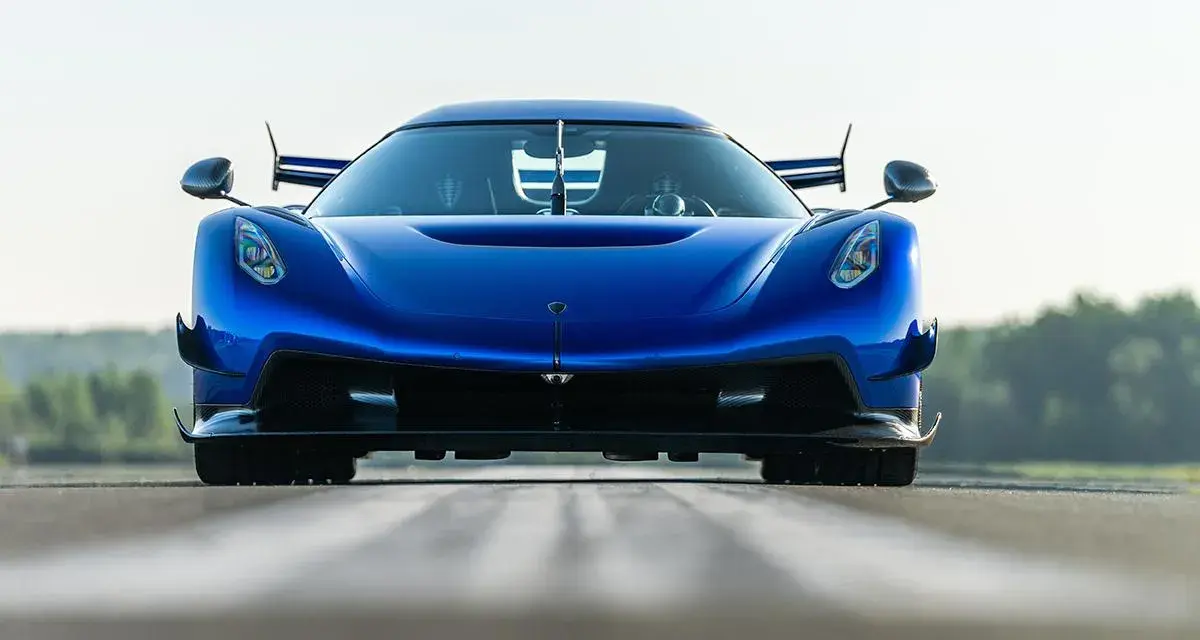 Niebieski Koenigsegg Jesko Attack z agresywnym przednim splitterem i spojlerami, gotowy do ataku na torze.