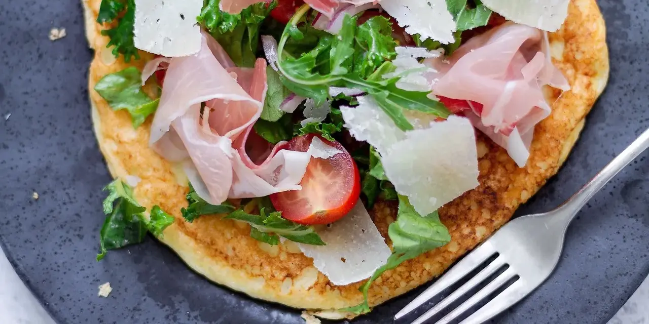 Pyszny przepis na omlet na słono z szynką parmeńską, parmezanem, pomidorkami i rukolą. Idealny na szybki obiad lub kolację.