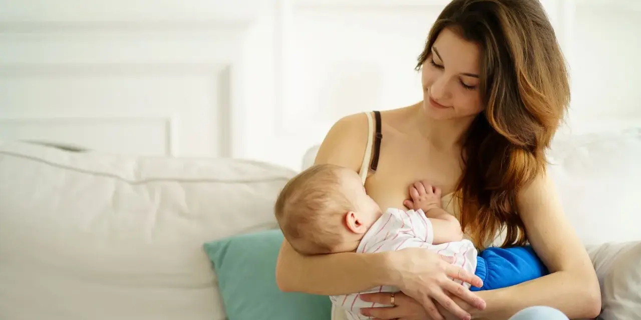 Ciepła chwila karmienia piersią. Mama z miłością patrzy na swoje dziecko, wspierając naturalną laktację.