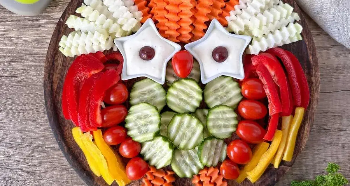 Eine bunte Rohkostplatte für Kinder, gestaltet als lustige Eule mit Sternen als Augen und verschiedenen Gemüsesorten.