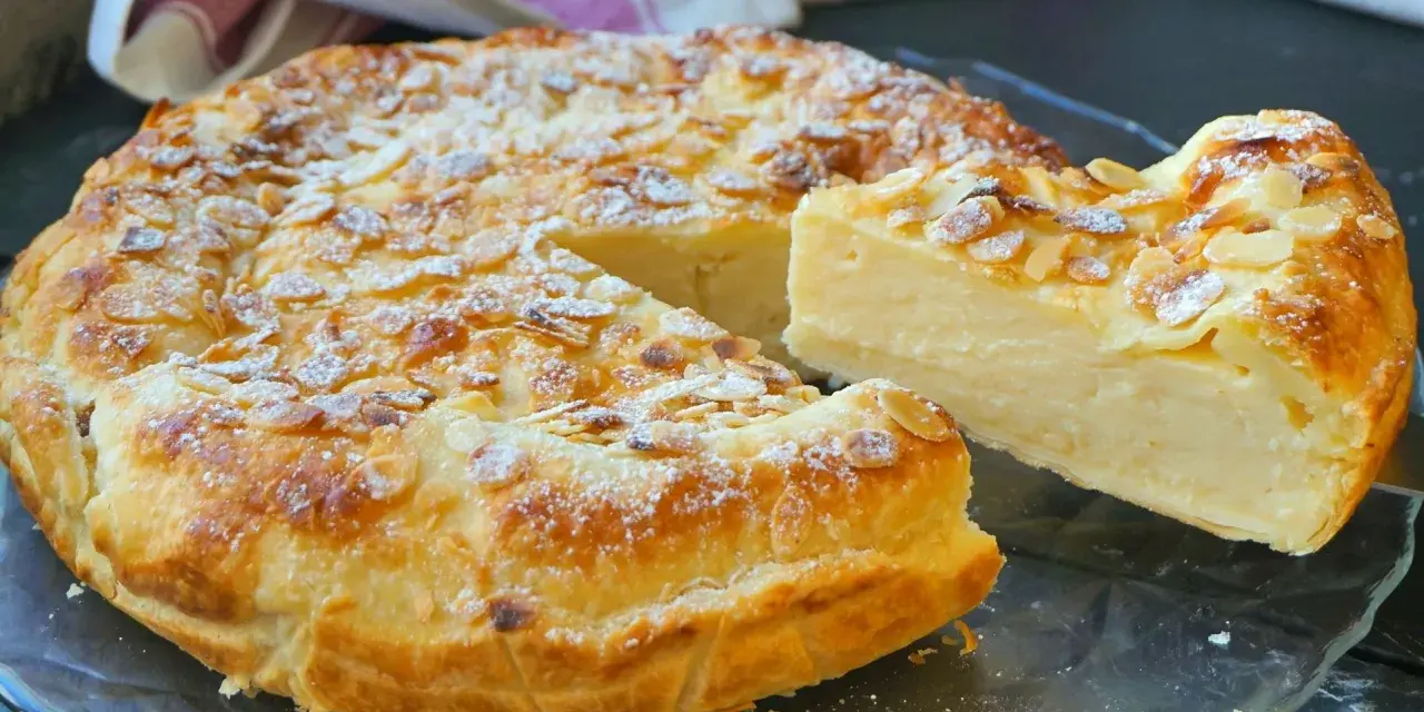 Tarta de hojaldre y crema pastelera, cubierta de almendras laminadas y espolvoreada con azúcar glas. ¡Un postre irresistible!