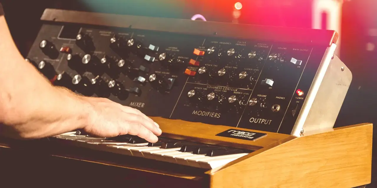 Hand spielt auf einem legendären Minimoog-Synthesizer, der den unverwechselbaren Sound der 70er Jahre prägte.