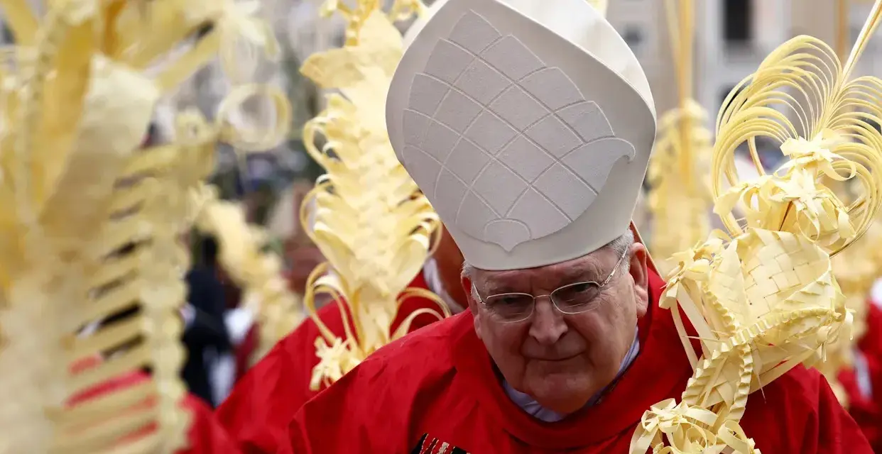 A bishop in red vestments and a white mitre holds a palm frond, surrounded by others. This scene marks Passion Sunday.