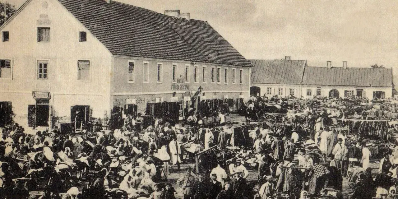 Tłum ludzi na targu w Biłgoraju, jakby żywcem wyjęty z legendy o tym mieście. W tle budynki i stragany.