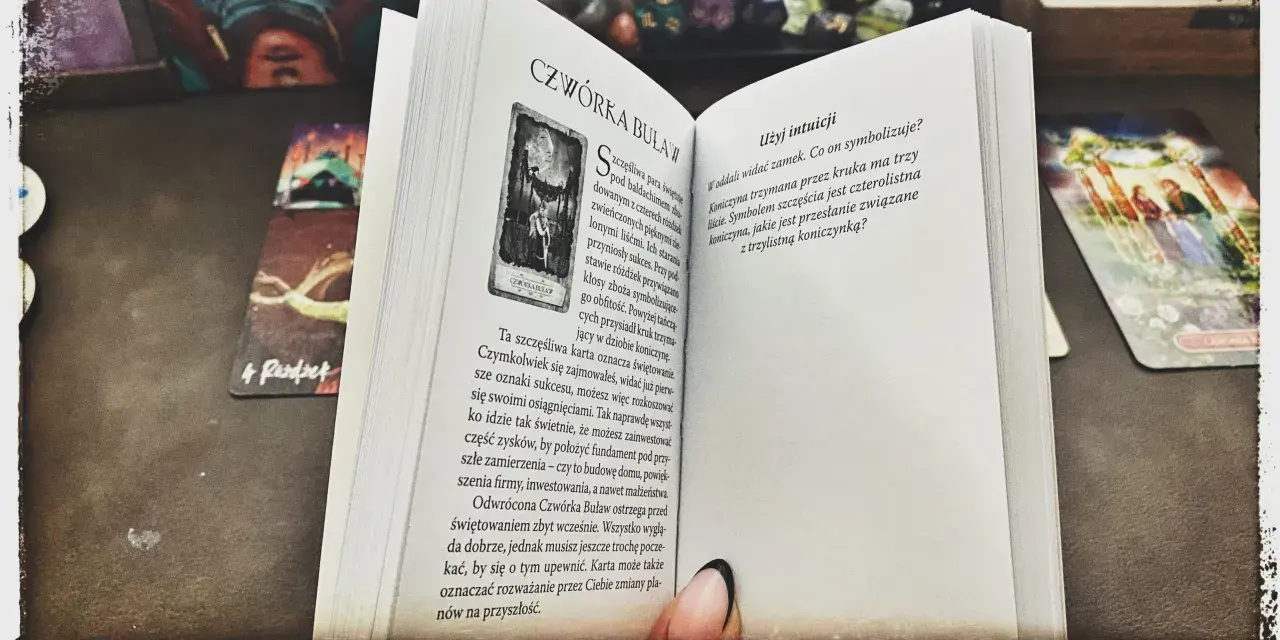 Mistycyzm i tarot marzyciela: otwarta księga z kartą "Czwórka Buław" i innymi kartami tarota.