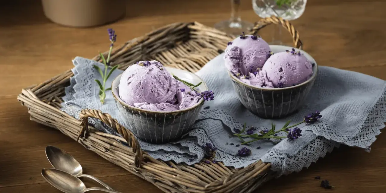 Zwei Schalen mit cremigem Lavendeleis, garniert mit Lavendelblüten. Ein köstliches Lavendeleis Rezept zum Nachmachen.