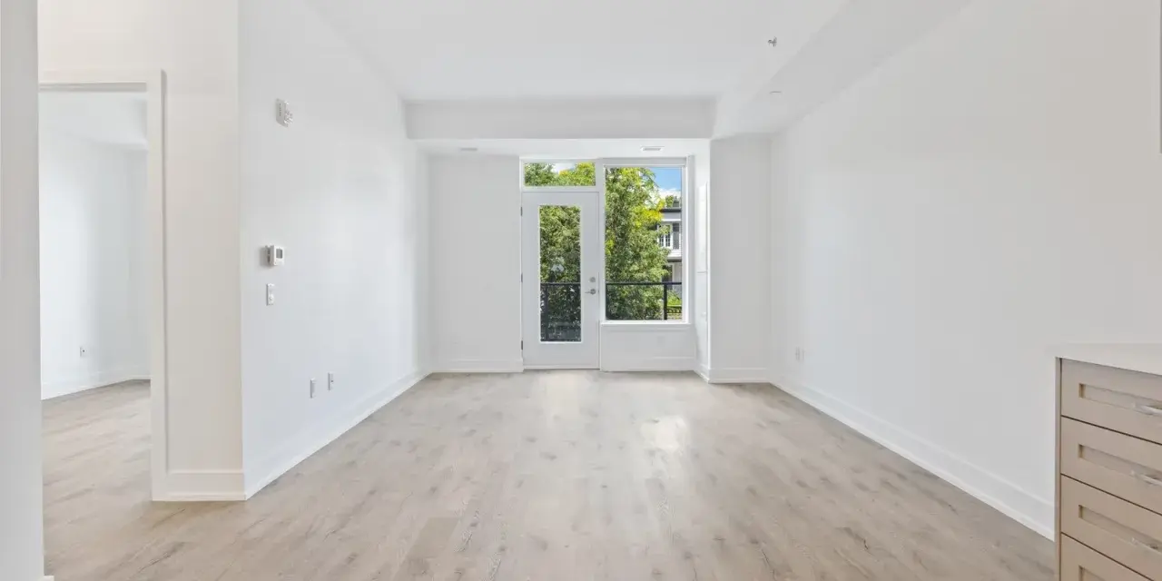 Salón luminoso con suelo de madera clara y puerta acristalada que da a un balcón. Ideal para vender piso heredado antes de 5 años.