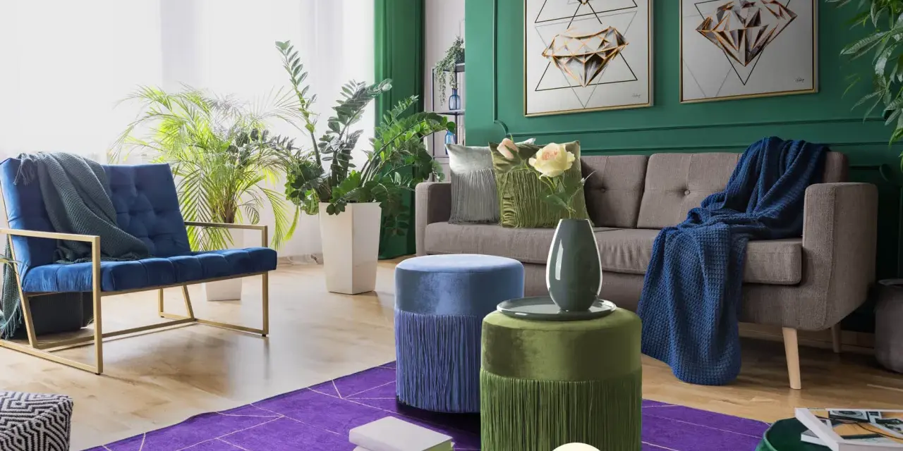 Elegancki salon z sofą, fotelem i pufami. Dominują głębokie zielenie, granat i fiolet. Pufy w odcieniach niebieskiego i **kolor seledynowy** dodają uroku.