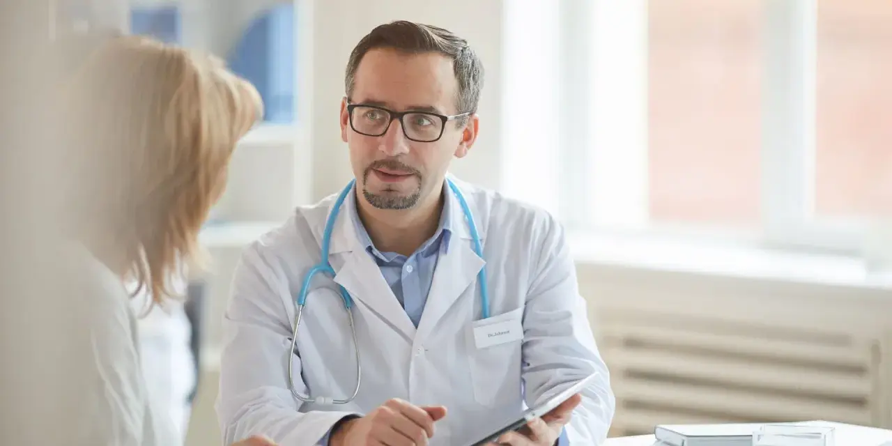 Arzt erklärt Patientin Ergebnisse, vielleicht den lipase wert, auf einem Tablet.