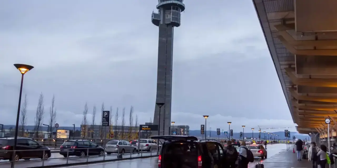 Wieża kontrolna na oslo lotnisko. Ludzie z bagażami wsiadają do vana.