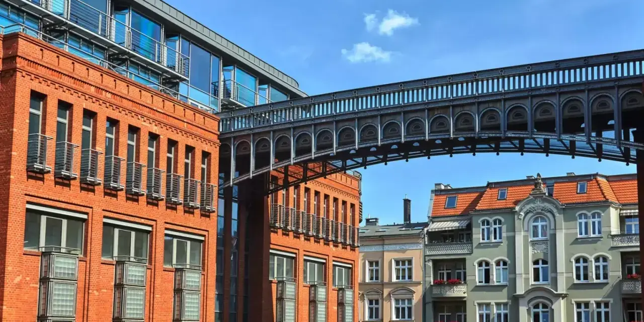 Nowoczesna architektura przeplata się z kamienicami, tworząc ciekawe **ukryte miejsca w Poznaniu**. Metalowy mostek łączy budynki.