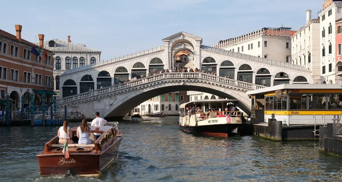 Gondola e vaporetti navigano sul Canal Grande sotto il maestoso Ponte di Rialto, un'icona di Venezia.