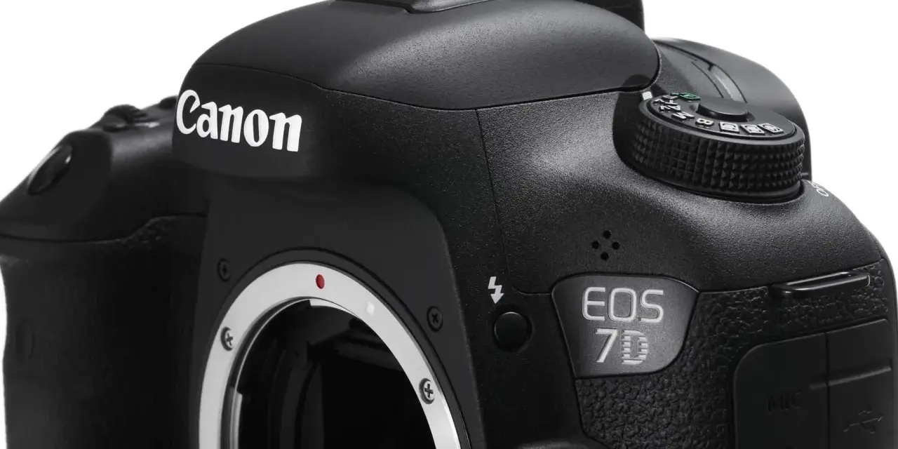 Czarne body aparatu Canon EOS 7D z widocznym obiektywem i pokrętłem trybów.