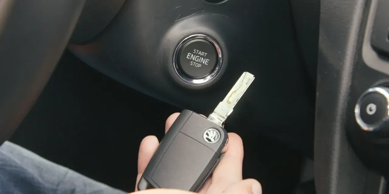 Słaba bateria w kluczyku może utrudnić odpalanie auta. Kluczyk z logo Skody leży w dłoni obok przycisku Start/Stop.