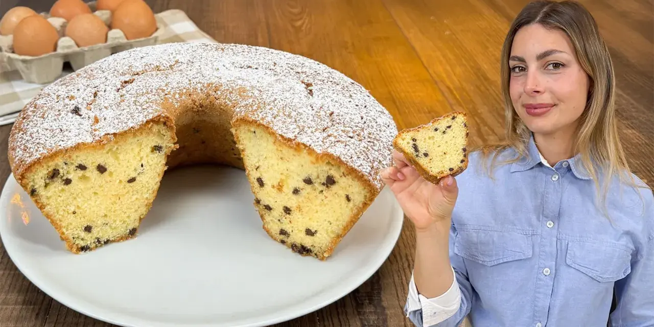 Un soffice ciambellone al bicchiere con gocce di cioccolato, spolverato di zucchero a velo, pronto per essere gustato.