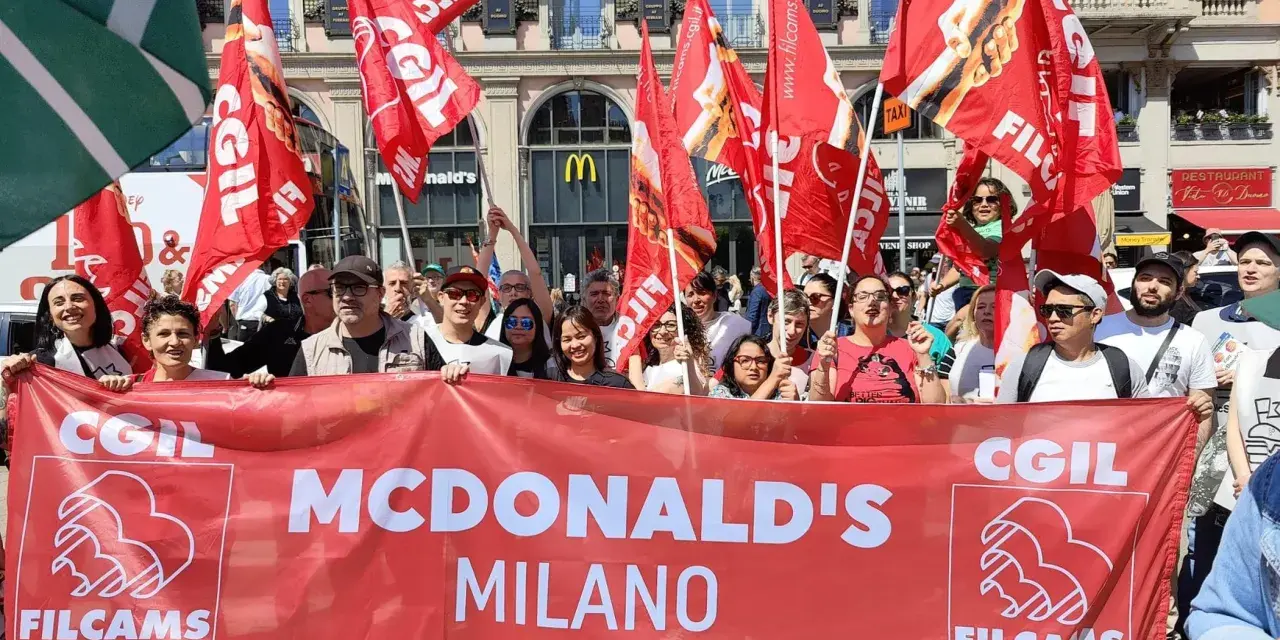 Manifestanti con bandiere rosse chiedono un miglior stipendio McDonald's a Milano.