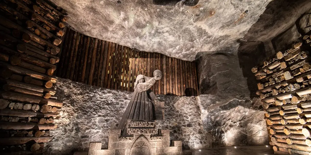 Kopalnia soli Wieliczka ciekawostki: rzeźba górnika Mikołaja Kopernika w solnej komorze, otoczona drewnianymi belkami i solnymi ścianami.