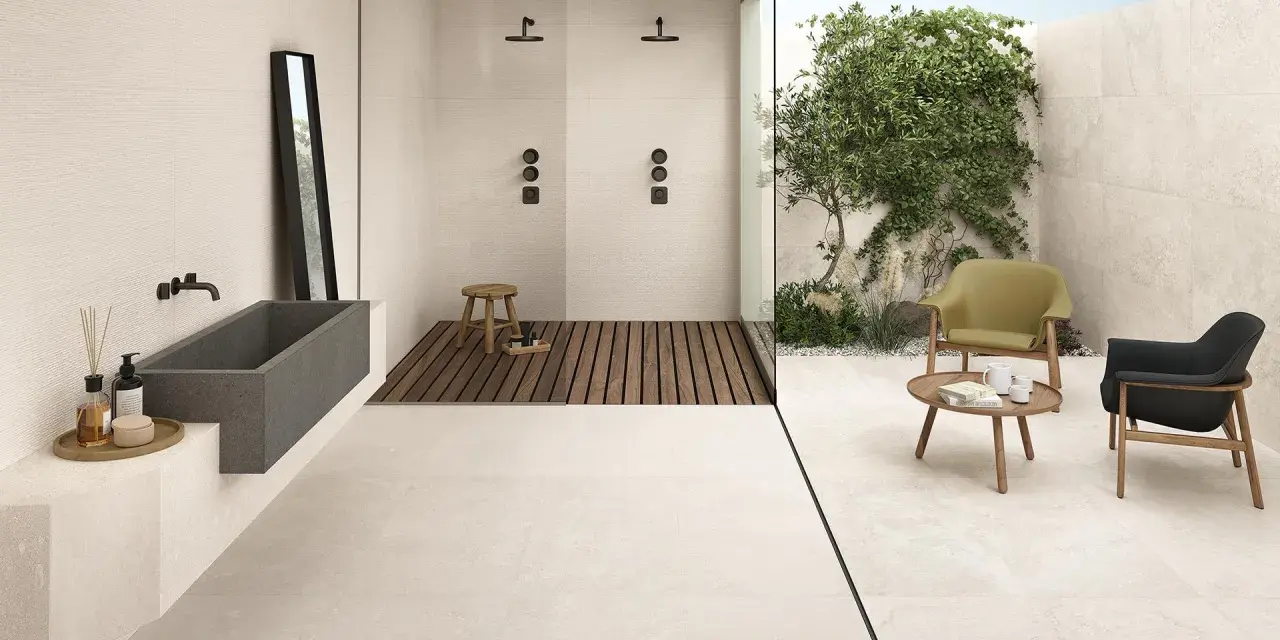 Un bagno moderno con vasca in pietra, doccia a filo pavimento e un'area relax esterna. Il pavimento casa mare crea un'atmosfera rilassante.