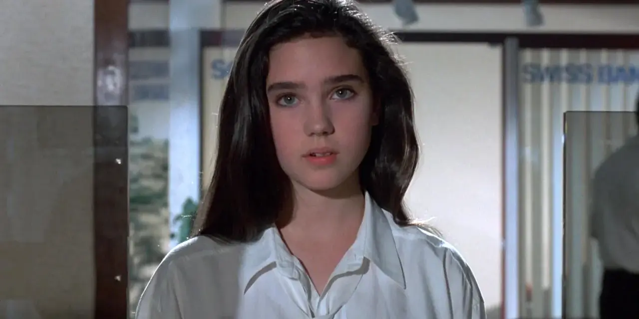Młoda Jennifer Connelly w białej koszuli, z charakterystycznym spojrzeniem, jak z jej wczesnych filmów.