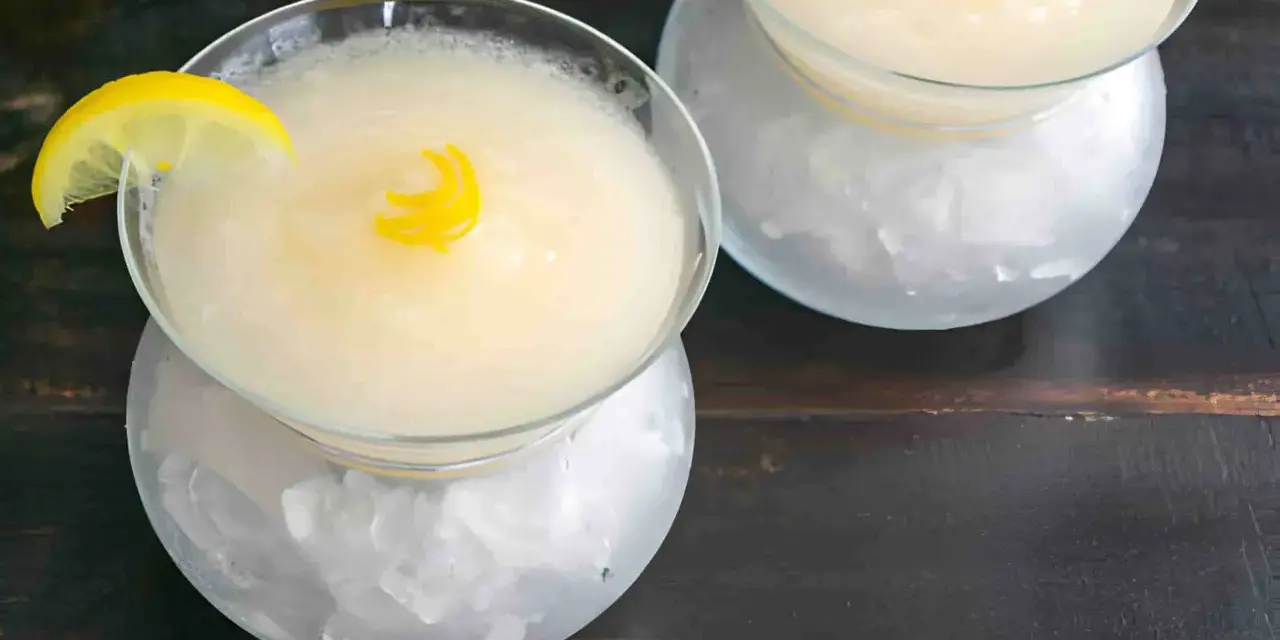Dos copas de sorbete de limón, una con rodaja de limón y rizo de cáscara, servidas sobre hielo picado.