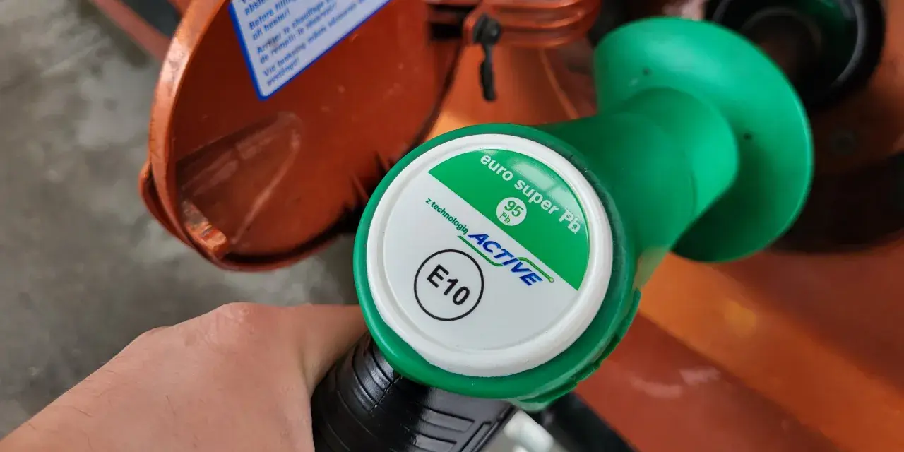 Dłoń trzyma zielony pistolet dystrybutora z napisem "euro super Pb 95 ACTIVE E10". To benzyna e10.