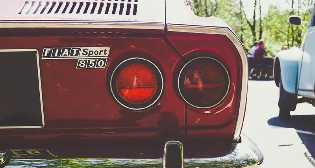 Dettaglio posteriore di una Fiat Sport 850 rossa, con i suoi iconici fanali rotondi. Un pezzo di storia automobilistica, un vero art 102 cds.