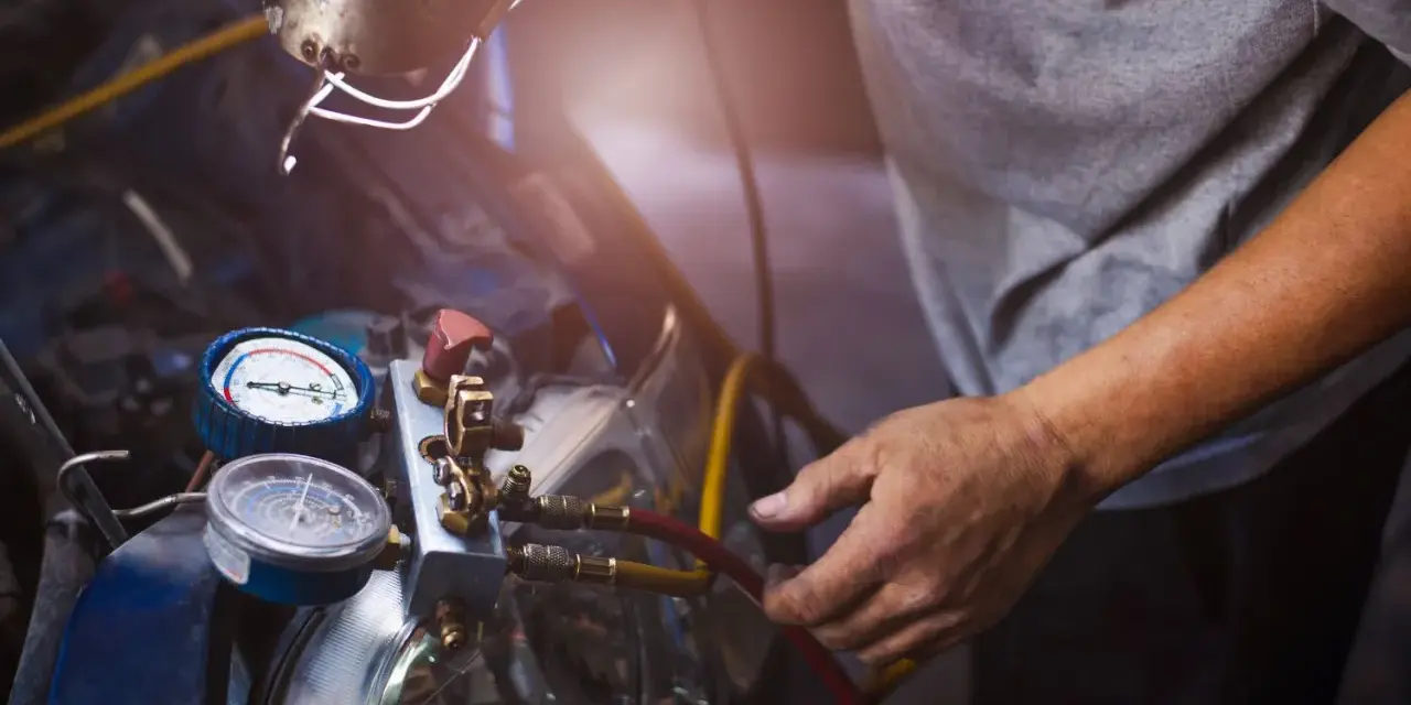 Mechanik sprawdza manometry układu klimatyzacji. Objawy zatarta sprężarka klimatyzacji mogą być widoczne na wskaźnikach.