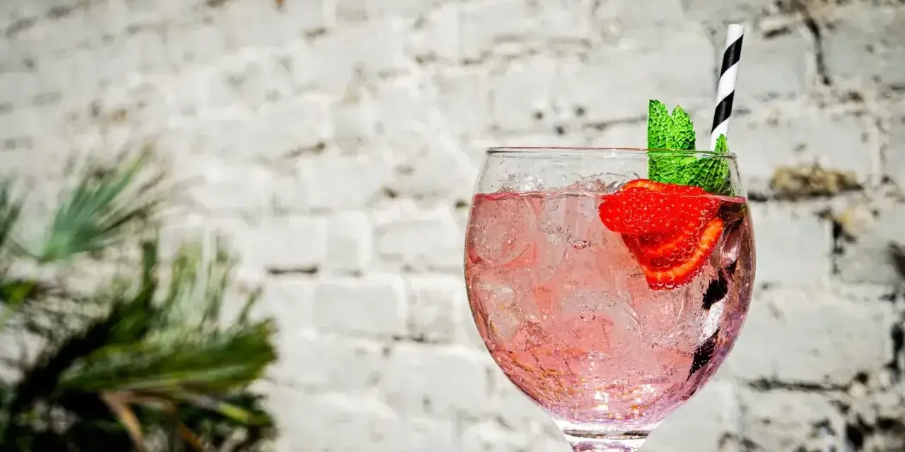 Orzeźwiający pink gin z lodem, truskawką i miętą, idealny na letnie popołudnie.