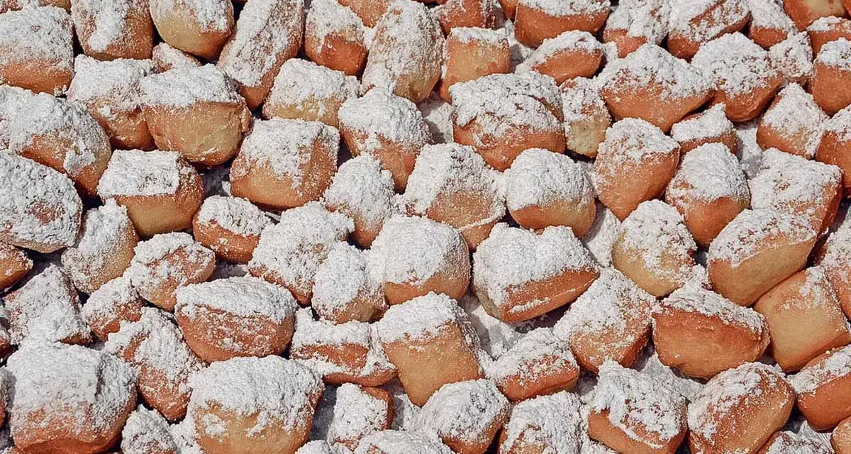 Ein Haufen goldbrauner, puderzuckerbestäubter Schmalzkuchen, die an ein schmalzkuchen originalrezept erinnern.
